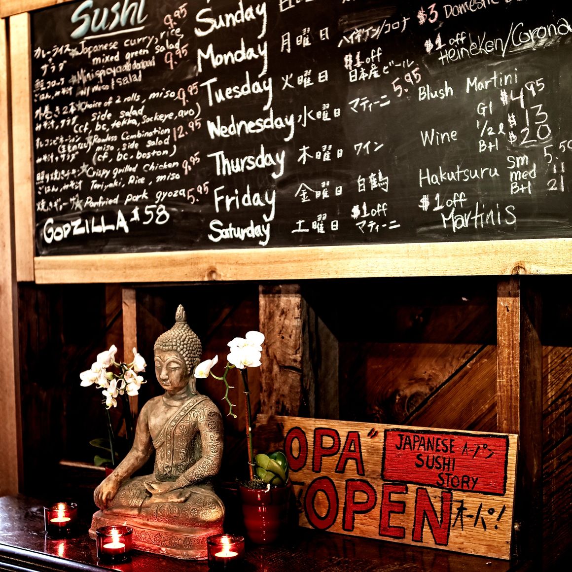 Opa Sushi interior with chalkboard menu, Buddha statue, candles, and hand-painted open sign.
